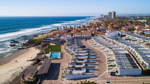 Een kusthotel met meerdere gebouwen, een strand en een steiger.