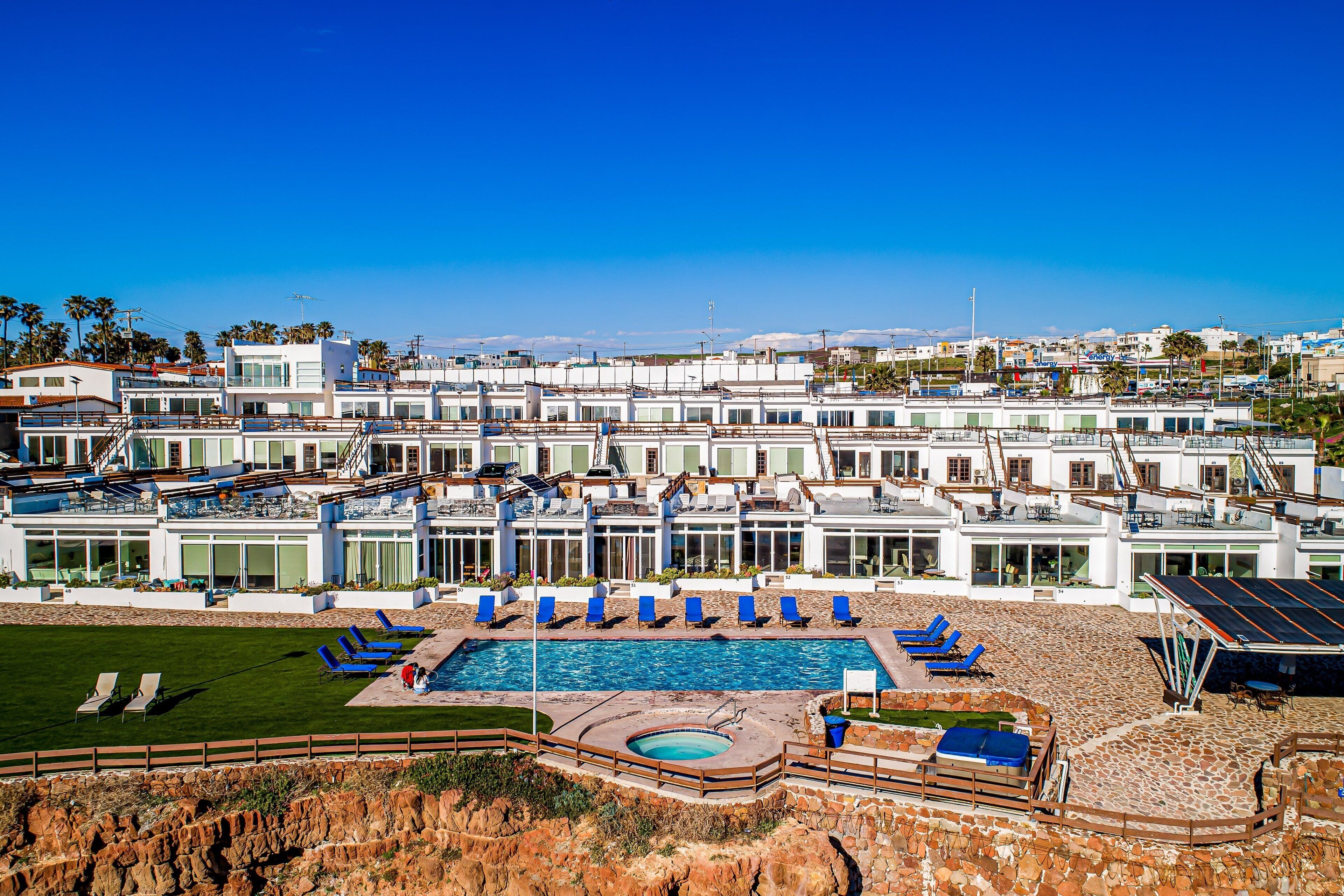 Ein modernes Hotel mit Schwimmbad, mehreren Lounges und Blick auf die Stadt.