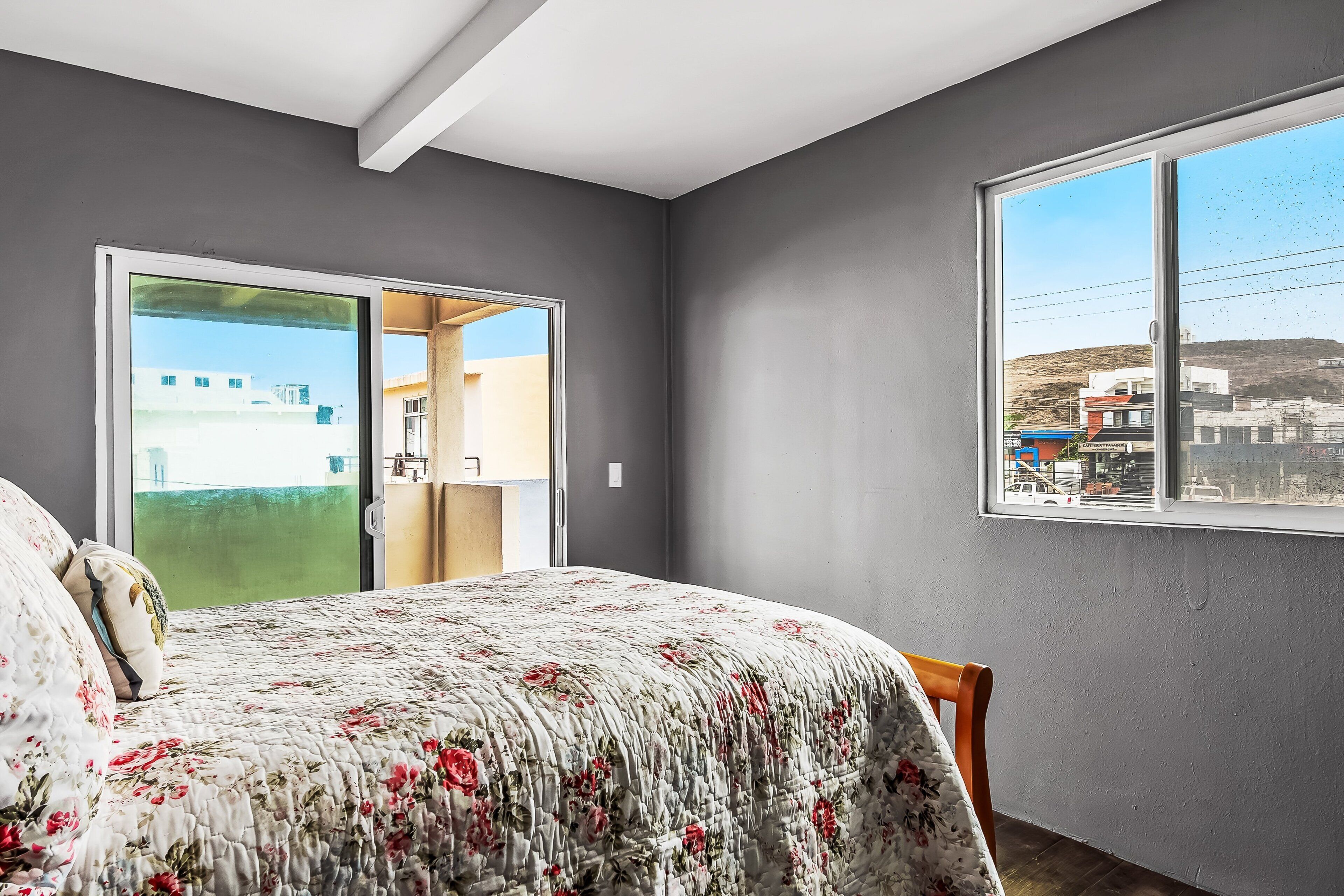 A bedroom with a bed, a window, and a door leading to an outdoor area.