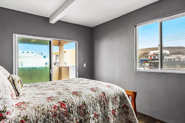 Un dormitorio con cama, ventana y puerta que da a un espacio al aire libre.