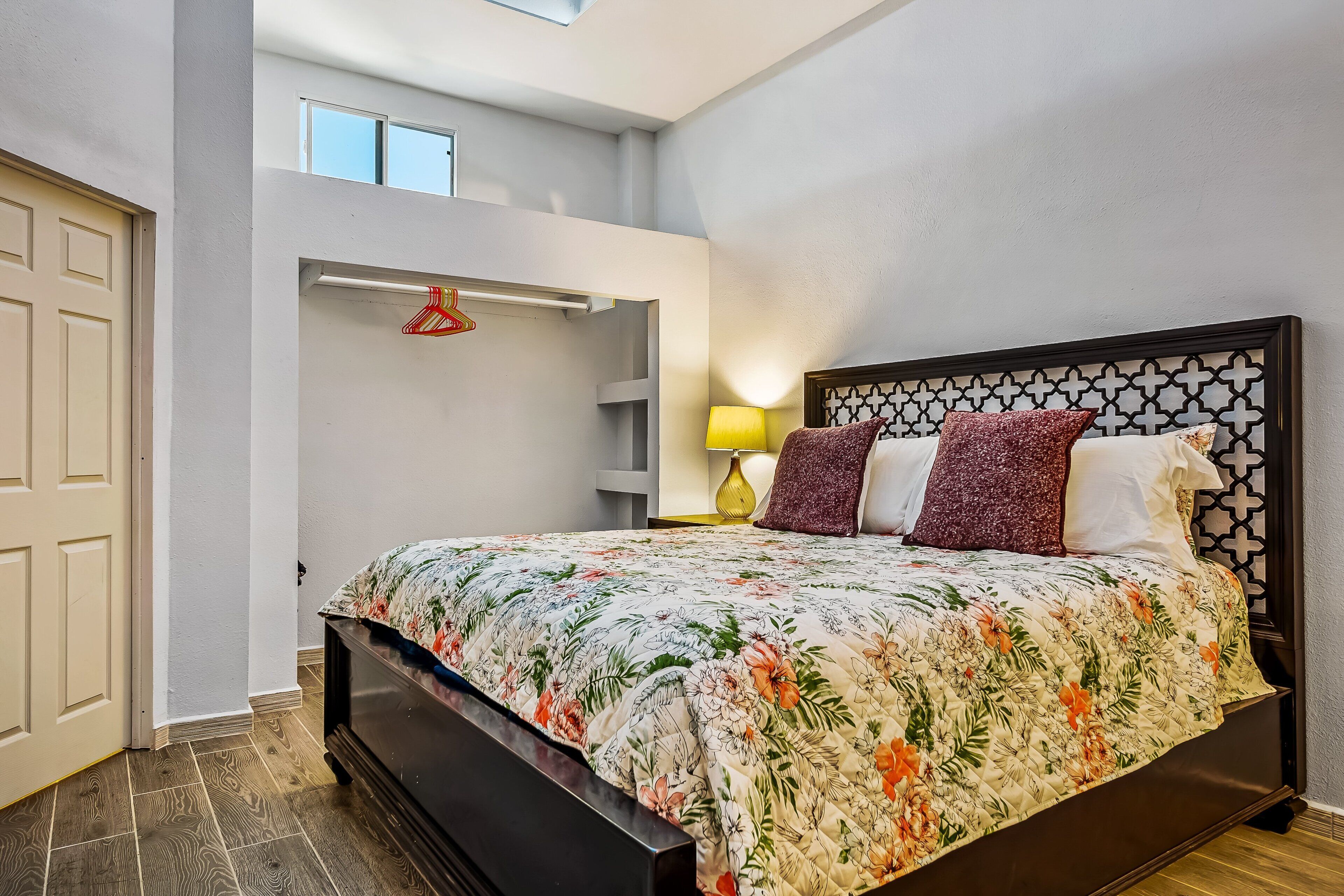 Une chambre à coucher avec un lit, une table de chevet, une lampe et une fenêtre.