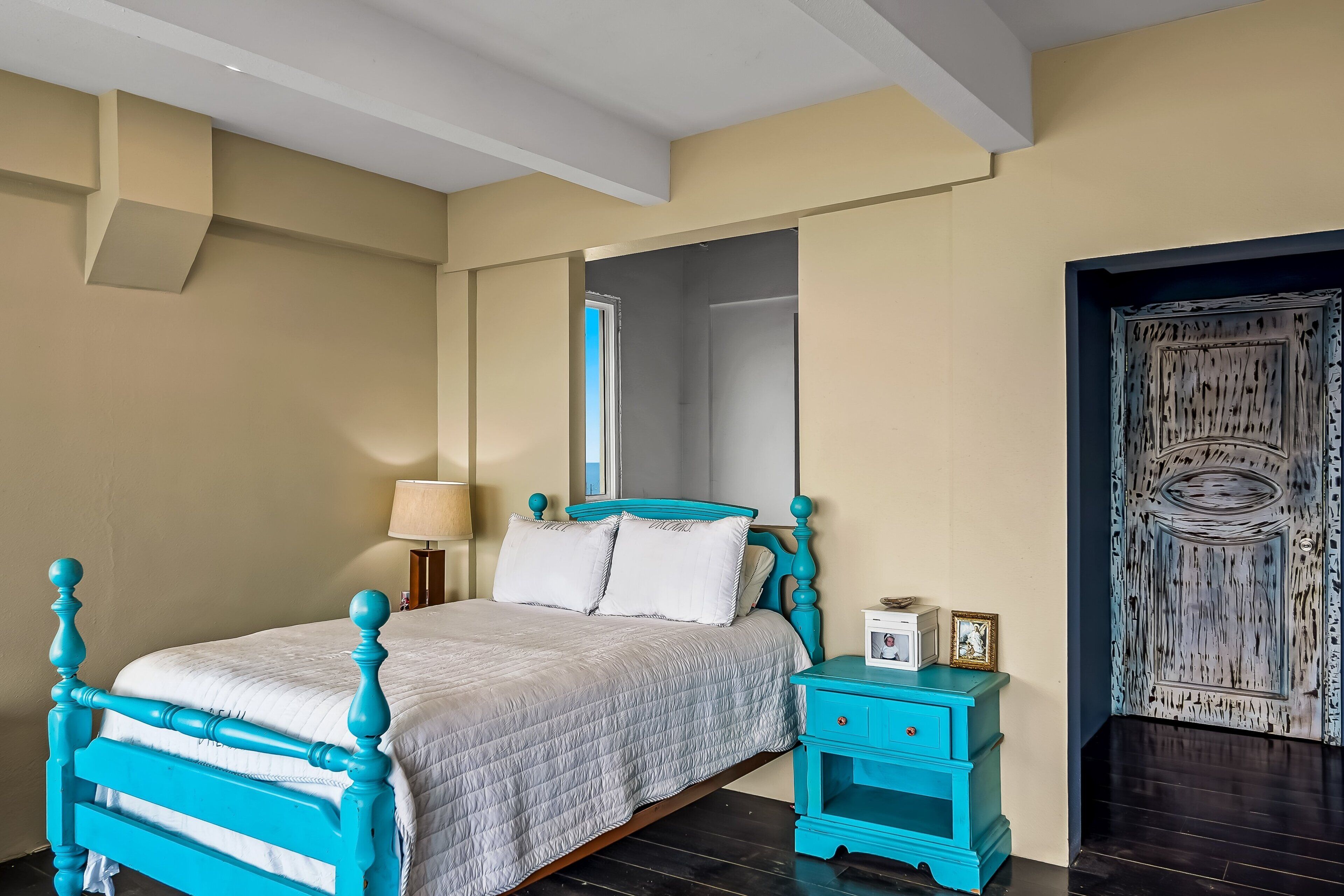 A bedroom with a bed, a nightstand, a mirror, and a door.