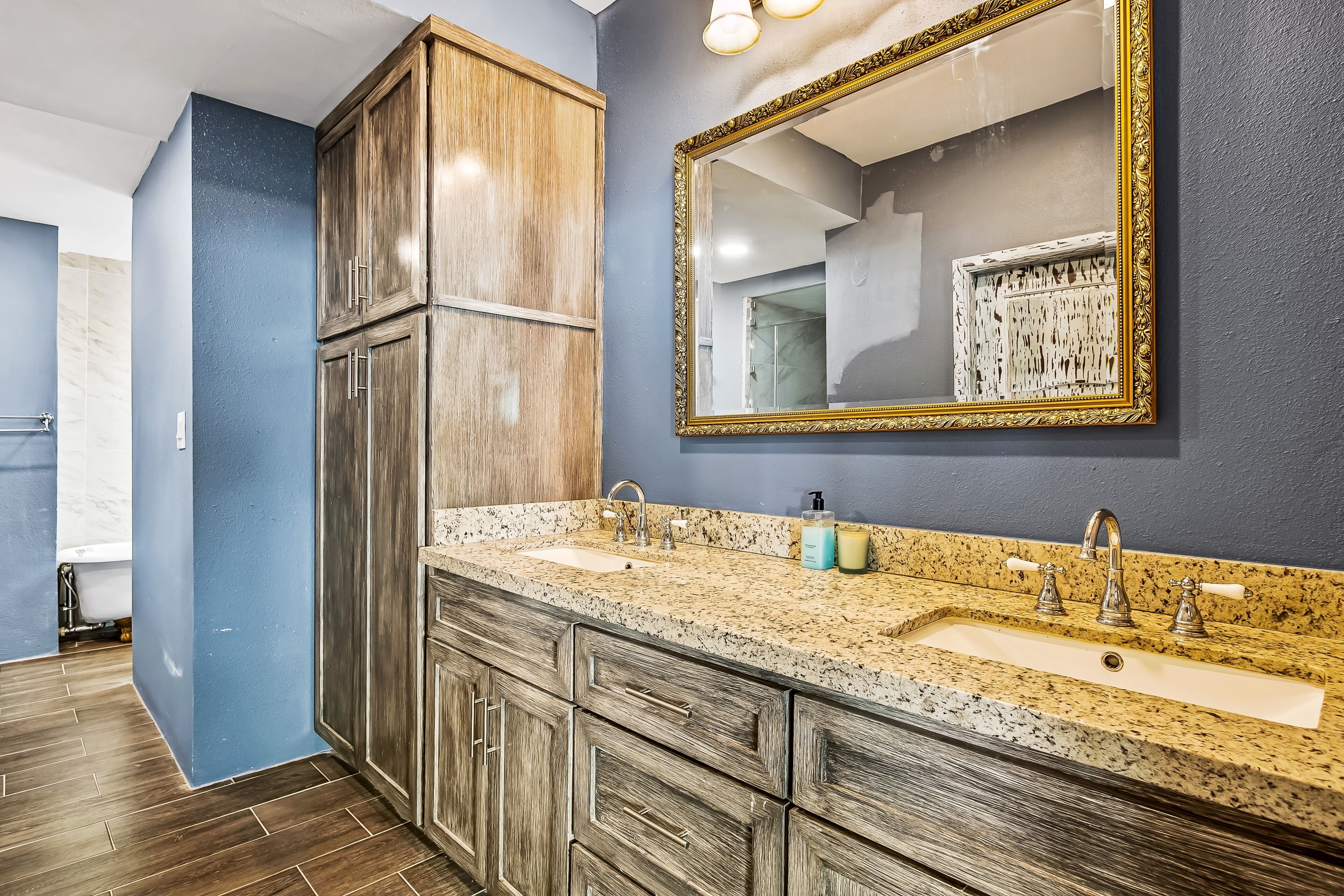 A bathroom with a double sink, wooden cabinets, and a large mirror.