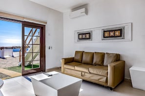 Ein Zimmer mit einem braunen Ledersofa, einem weißen Couchtisch und einer Glastür, die auf einen Balkon führt.
