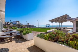 Eine Terrasse mit Sitzgelegenheit, Blick auf den Strand und eine Pergola.