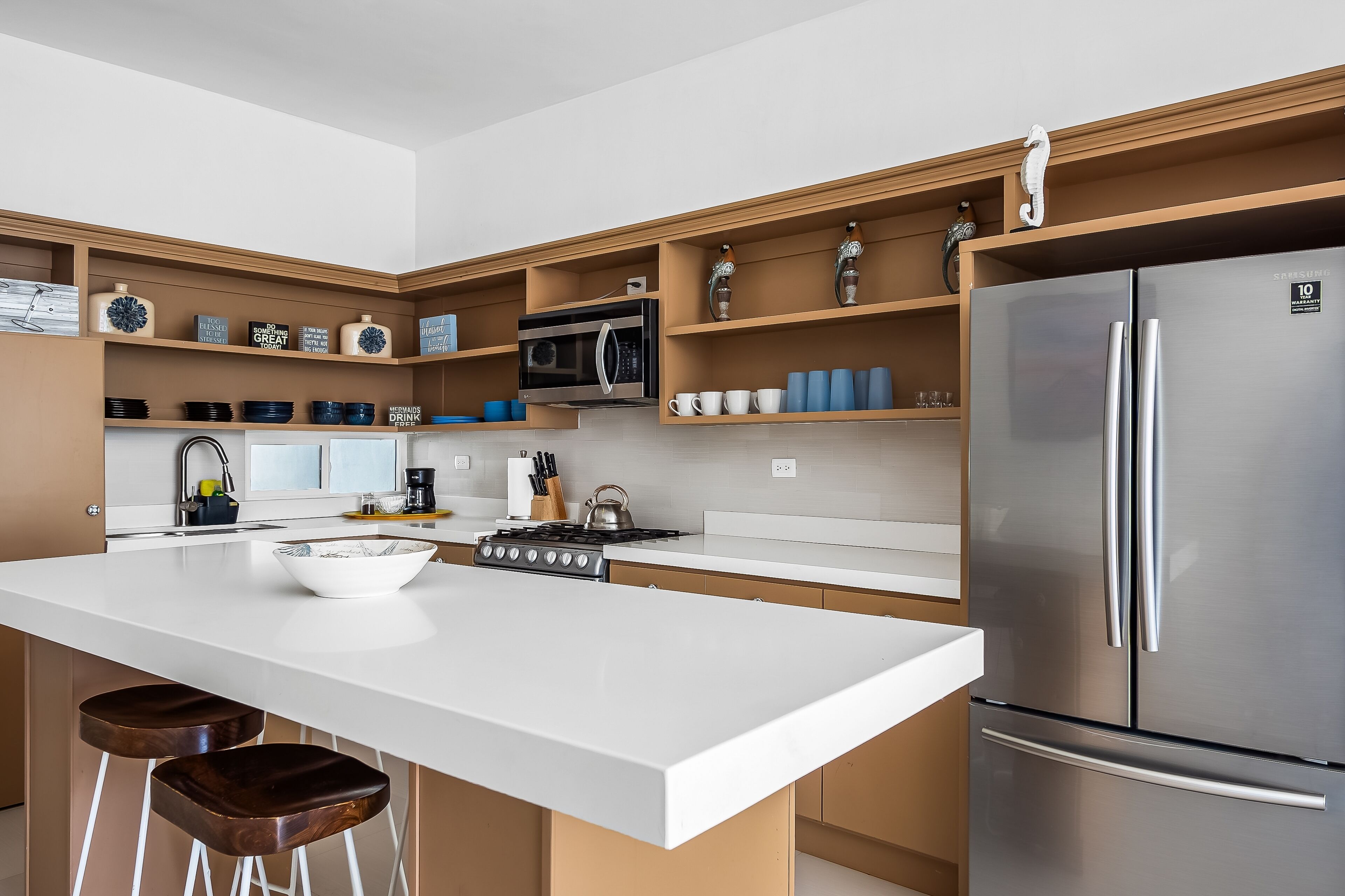 A modern kitchen with a central island, stainless steel appliances, and wooden shelves.