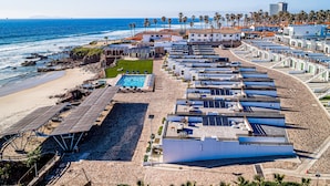 Hotel a la costa amb diverses piscines al terrat, una zona de platja i vistes a l'oceà.