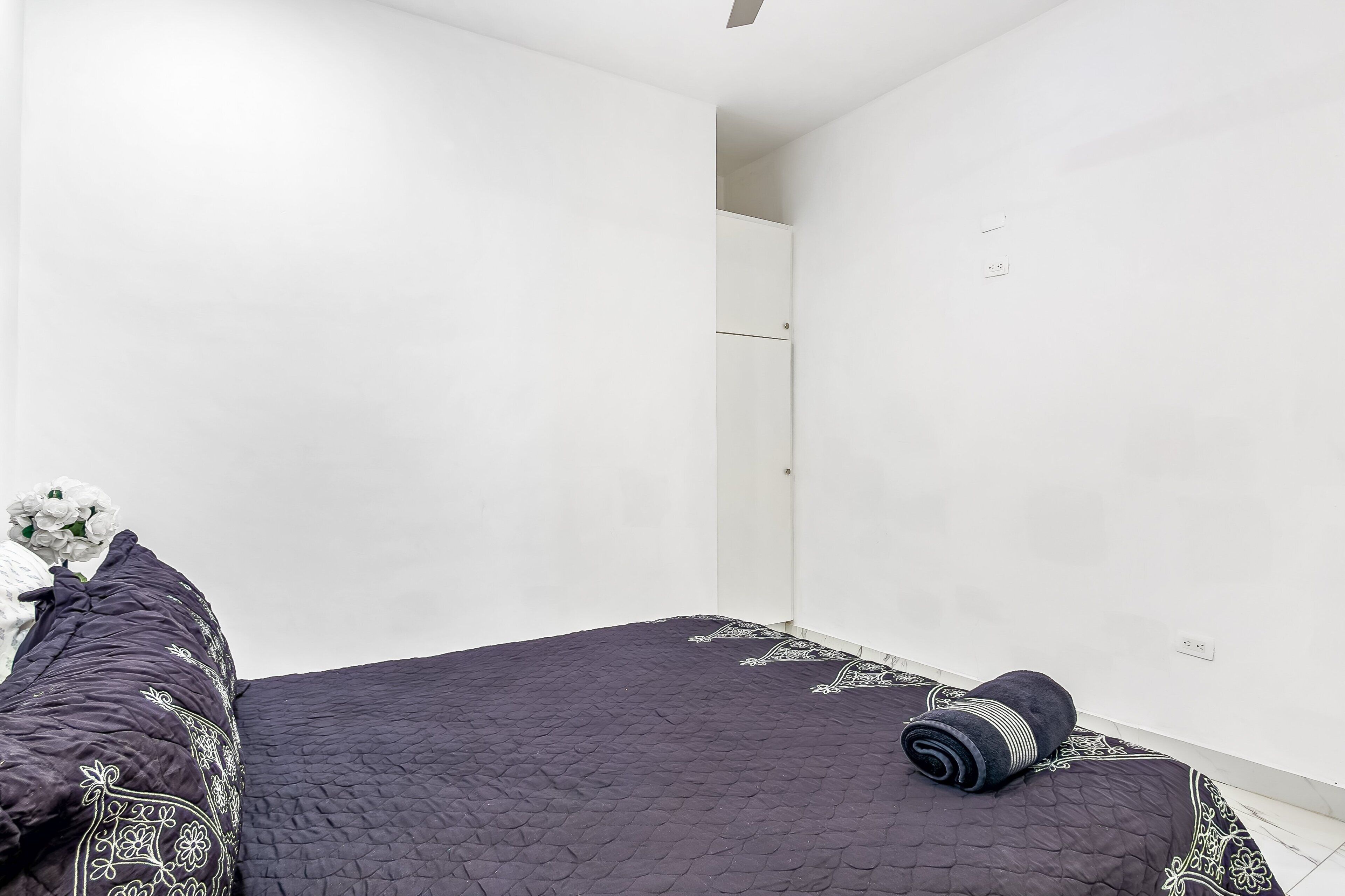 Une chambre à coucher avec un lit, un oreiller, une serviette enroulée et une porte.