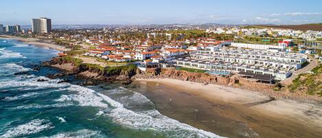 A coastal area with a beachfront resort, including a sandy beach and ocean waves.