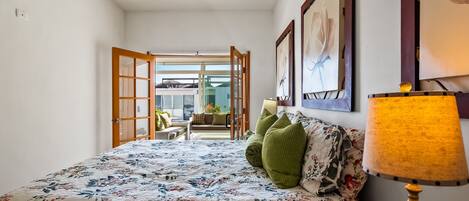 Un dormitorio con cama, lámpara y vistas a un balcón exterior.