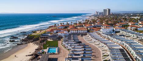 A coastal hotel with multiple buildings, a beach, and a pier.