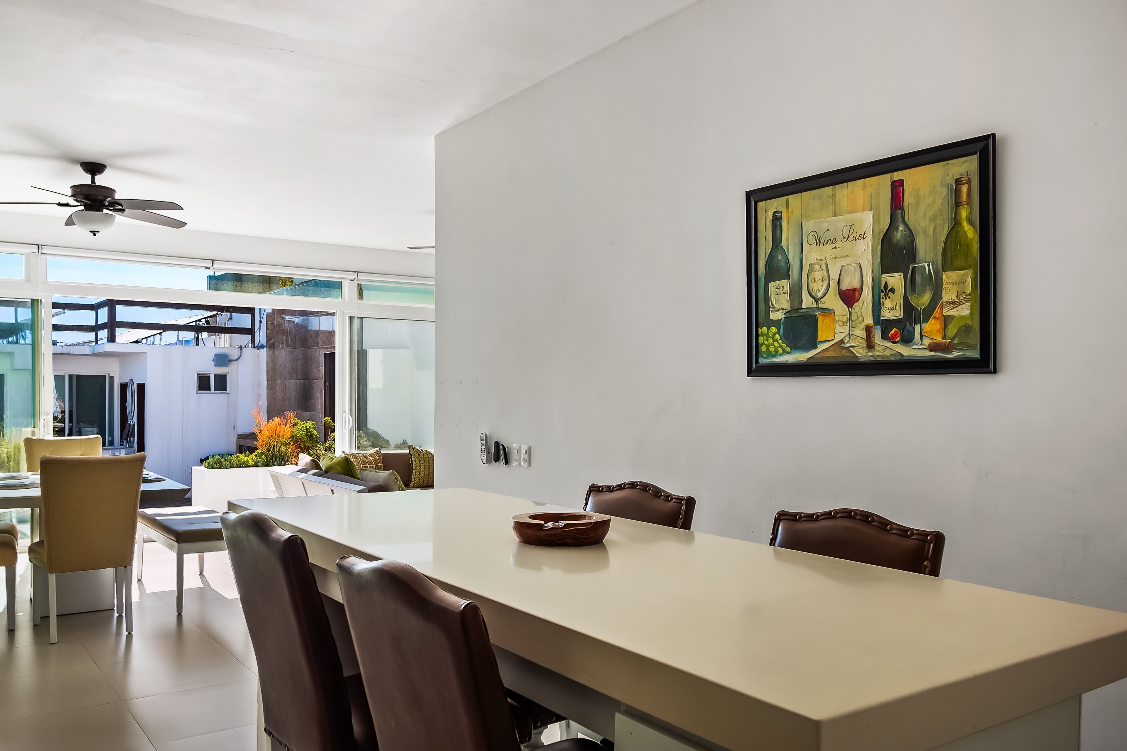 A dining area with a long table, chairs, and a ceiling fan.