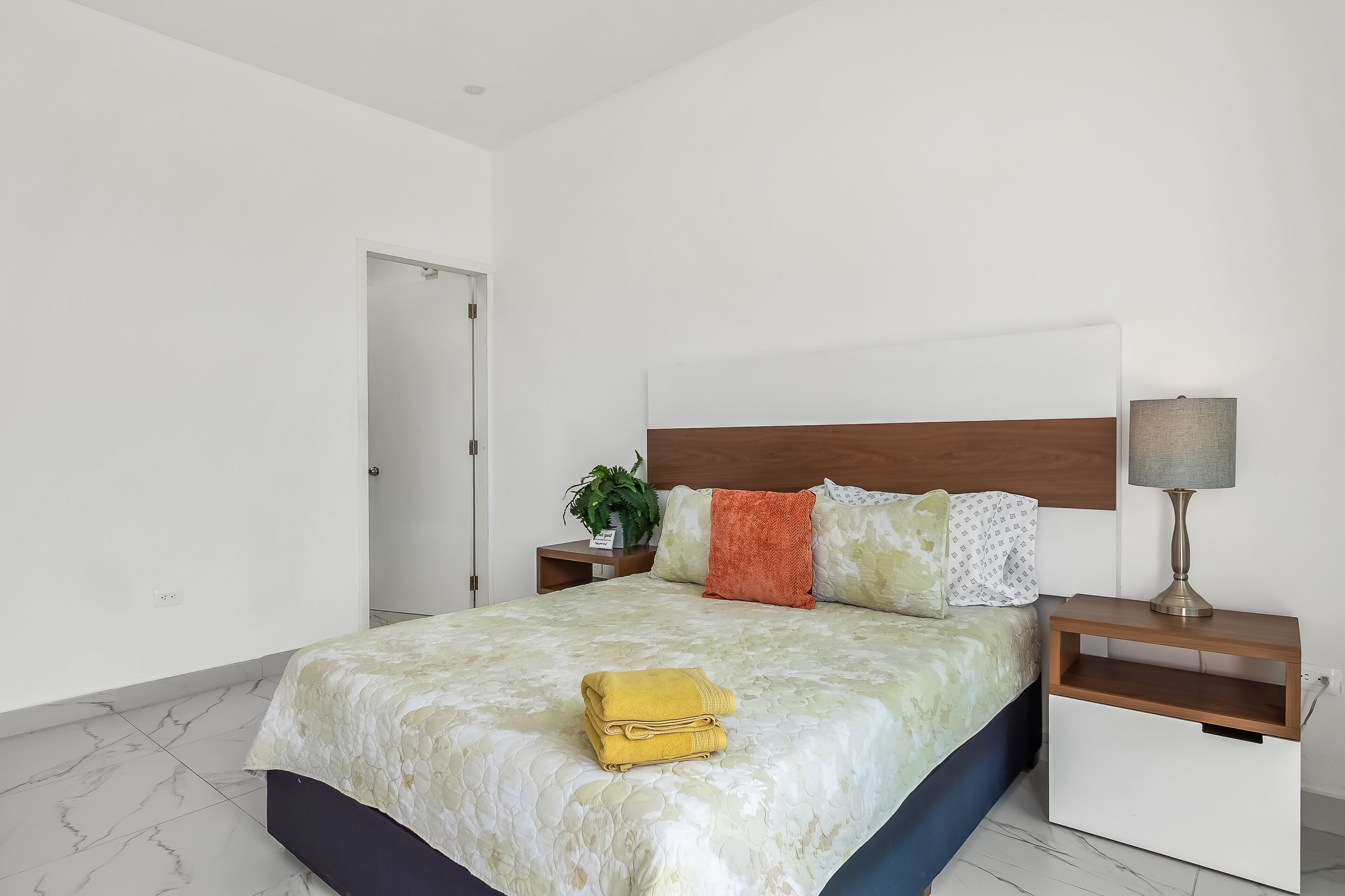 A bedroom with a bed, nightstands, a lamp, and a door.