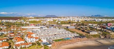 A coastal residential area with white buildings, a beach, and a clear blue sky.