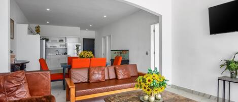 Ein modernes Wohnzimmer mit einer Couch, einem Couchtisch und einem an der Wand montierten Fernseher.