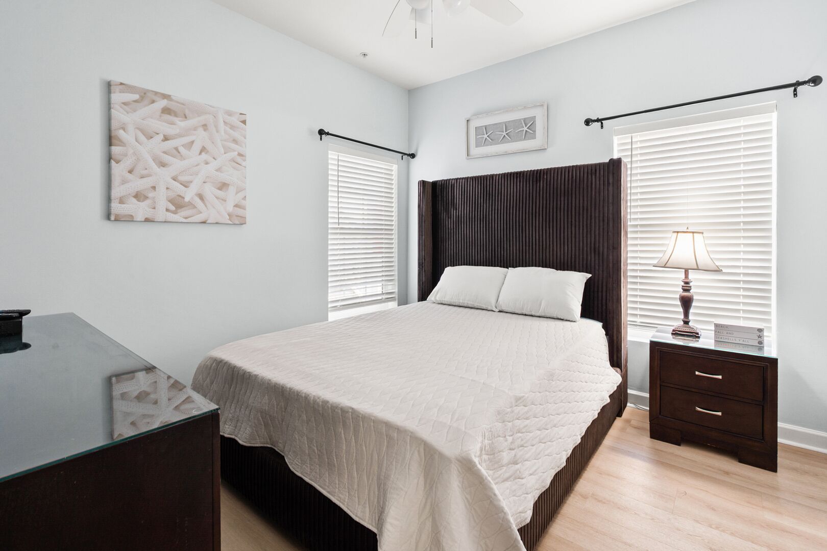 A bedroom with a bed, bedside tables, a desk, and a ceiling fan.