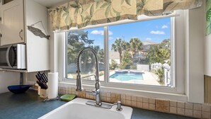 Eine Küche mit Spüle, einem Fenster mit Blick auf einen Swimmingpool und einer Mikrowelle.