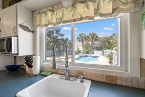 Eine Küche mit Spüle, einem Fenster mit Blick auf einen Swimmingpool und einer Mikrowelle.