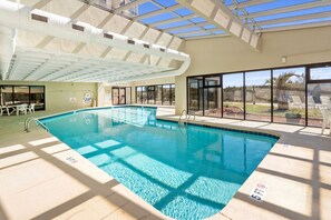Ein Innenpool mit klaren Glasdecken, einem sonnendurchfluteten Poolbereich und Blick ins Freie.