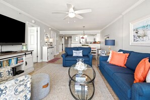 A living room with a TV, sofa, ottoman, and coffee table. - Oceanfront 3BR condo with indoor pool, lazy river, hot tub, and private balcony in Cherry Grove (North Myrtle Beach)