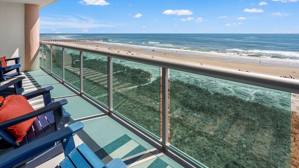 Een balkon met uitzicht op strand en zee.