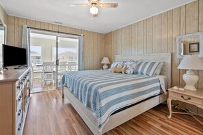 Ein Schlafzimmer mit Bett, Fernseher, Schminktisch, Nachttisch und Balkon.