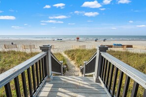 A wooden boardwalk leading to a beach with a lifeguard tower. - Bahama Sands 901- a luxury ocean view condo in North Myrtle Beach (North Myrtle Beach)