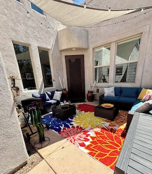 En overdækket terrasse med en blå sofa, et tæppe med mønster og en pyntet dør.