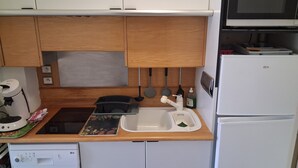 Une cuisine compacte équipée d’un four à micro-ondes, d’un évier et d’un lave-vaisselle.