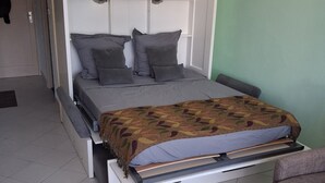 Un lit avec une tête de lit, des oreillers et une couverture à motifs.