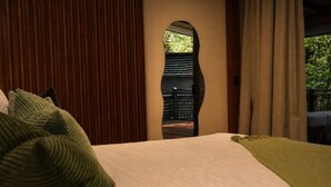 Une chambre avec un lit, une vue à travers une fenêtre en arc de cercle et un balcon.