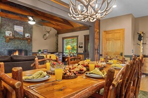 A dining area with rustic wooden furniture, a fireplace, and a chandelier. - Franklin NC Cabin Sleeps 10, Hot Tub, Game Room (Franklin)