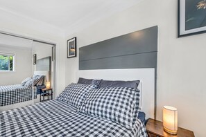 Une chambre à coucher avec un lit, une table de chevet, une lampe et un miroir.