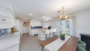 Une cuisine moderne avec des meubles blancs, un îlot central et un lustre.