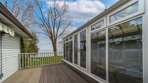 Une terrasse couverte avec une balustrade, de grandes fenêtres et une vue sur un arbre et le ciel.