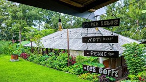 A rustic wooden building with signs indicating 'HK MI REBUS,' 'ROTI Bakar,' 'PISANG Keju,' and 'ICE COFFEE.' - Cozzy Villa Hajeka (Pangalengan)