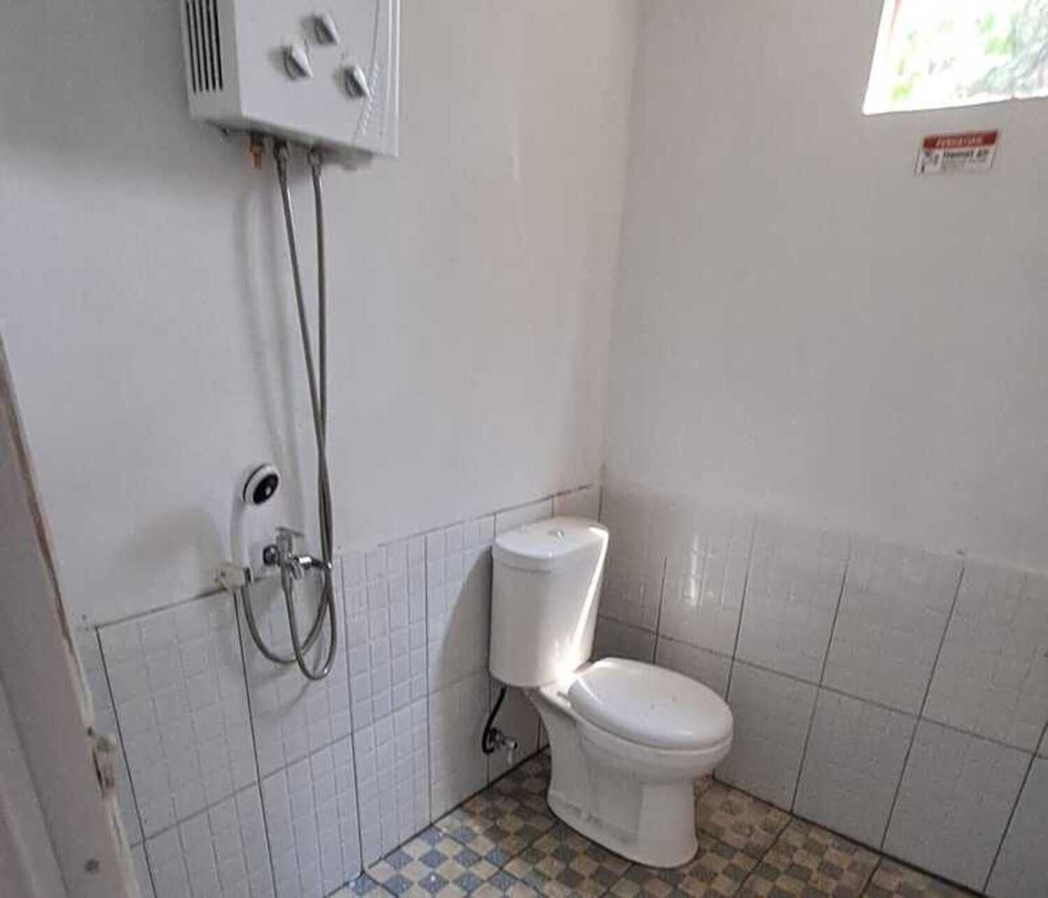 A small bathroom with a toilet, a shower, and a wall-mounted heater.