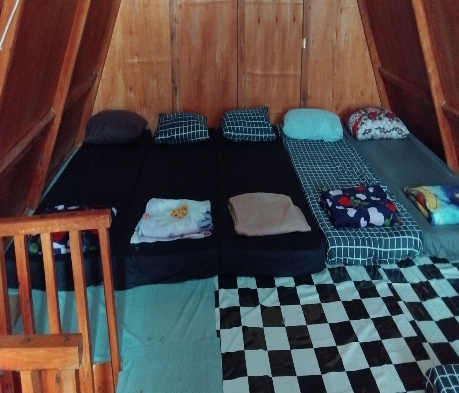 Una carpa con dos camas, almohadas, una silla de madera y un suelo a cuadros.