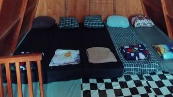 A tent with two beds, pillows, a wooden chair, and a checkered floor.