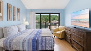 Ein Schlafzimmer mit Bett, Fernseher, Sessel, Kommode und einem Balkon mit Blick.