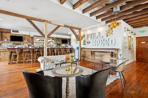 Eine großzügige Bar mit Holzbalken, einem weißen Sofa und einem runden Tisch mit Stühlen.