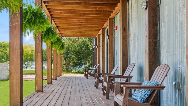 A wooden deck with Adirondack chairs, a pergola, and a view of a green landscape. - Commander 6 Farragut Lofts, Old Town, City Park (Bay Saint Louis)