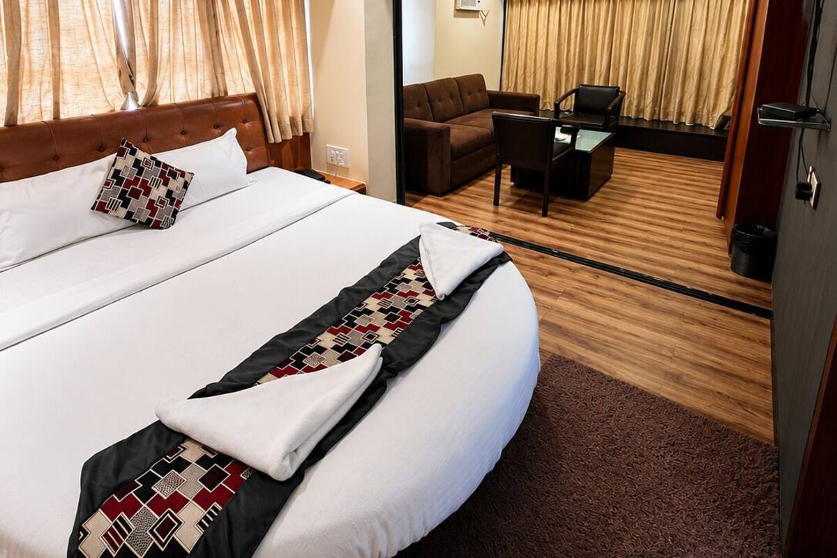 Ein Hotelzimmer mit einem großen Bett, einem Deckenventilator, einem Schreibtisch mit Stuhl und einem Fernseher.
