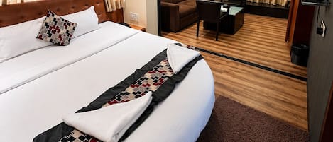 A hotel room with a large bed, a ceiling fan, a desk with a chair, and a television.