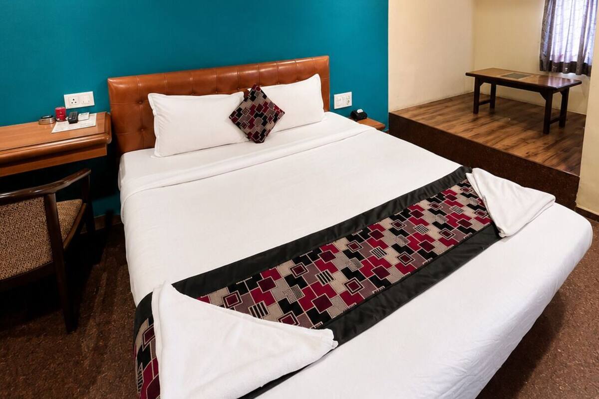 Ein Hotelzimmer mit Bett, Schreibtisch, Stuhl, Deckenventilator und Klimaanlage.