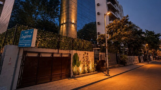 A modern building with a glass facade, a sign for 'Jayshree Hotels,' and a well-lit entrance. - Glitz Hotel Jayshree - Nr Mumbai Airport (Mumbai)