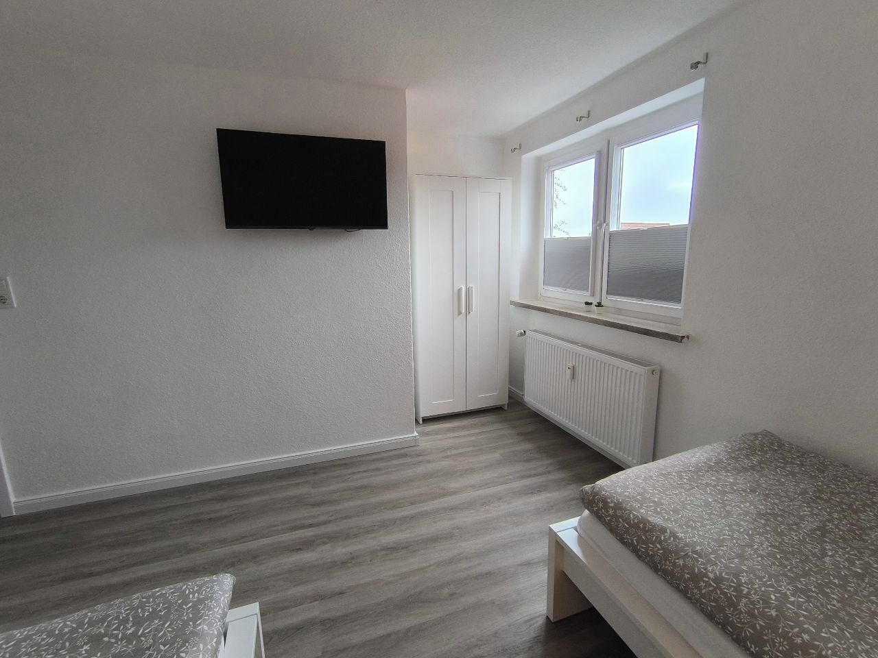Une chambre à coucher avec un lit, une télévision, une armoire et une fenêtre.