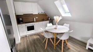 A modern kitchen with white cabinets, a wooden countertop, and a dining area with a white table and chairs. - Beautiful large apartment with super roof terrace (Walsrode)