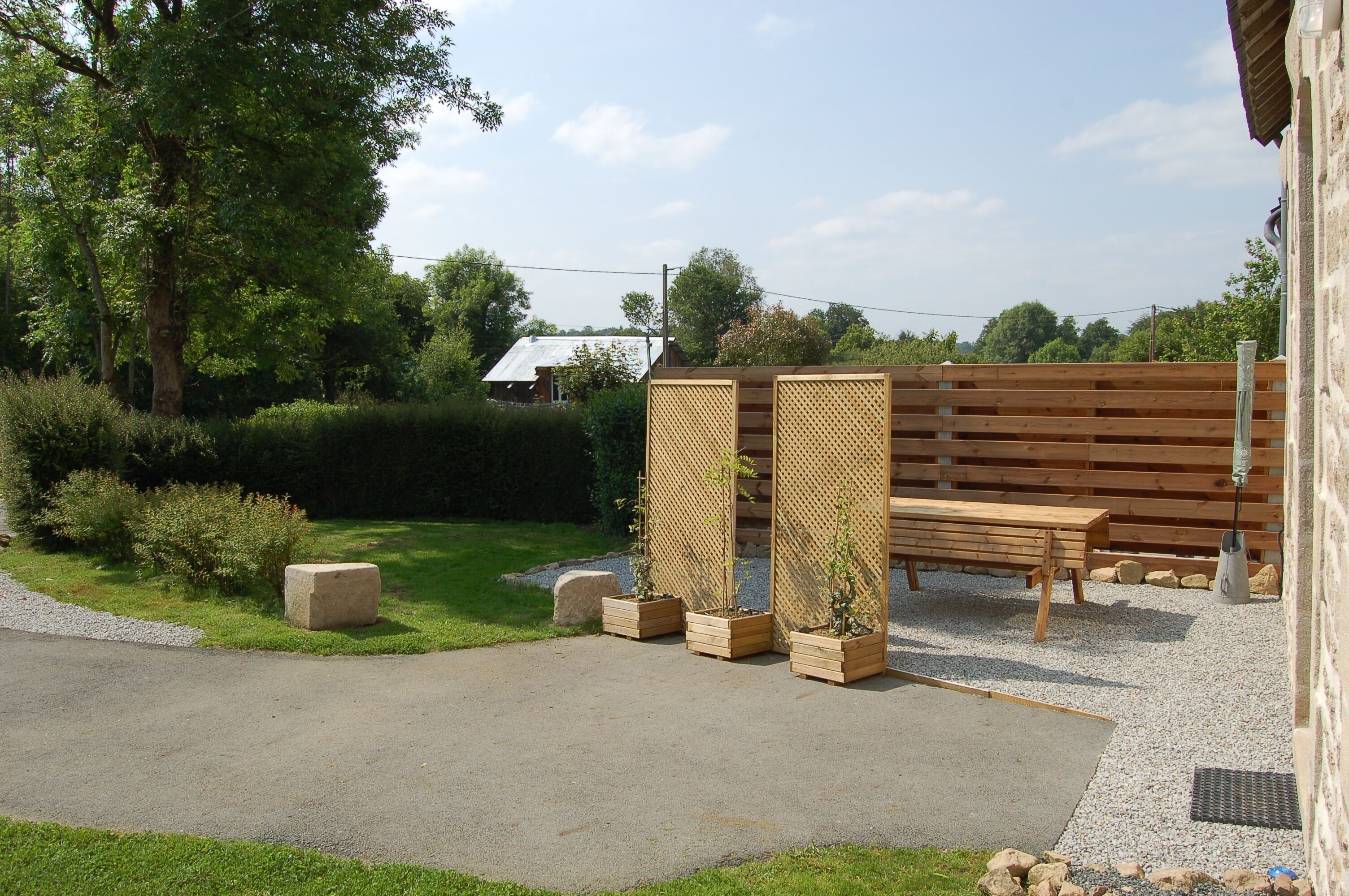 Ein Garten mit einer Holzbank, einem Holzzaun und einem Betonpflanzgefäß mit einer Pflanze.