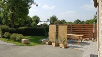 Ein Garten mit einer Holzbank, einem Holzzaun und einem Betonpflanzgefäß mit einer Pflanze.